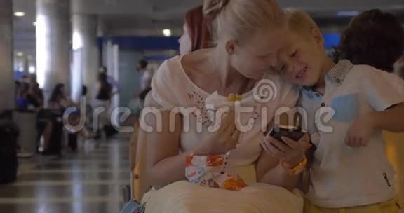 有手机的母子在机场休息室视频的预览图