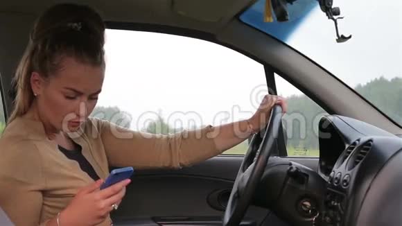 坐在车后的年轻女孩使用智能手机视频的预览图