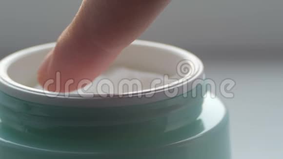 绿罐带着化妆品温和的奶油女性手指触摸奶油近距离观看奶油大指法视频的预览图