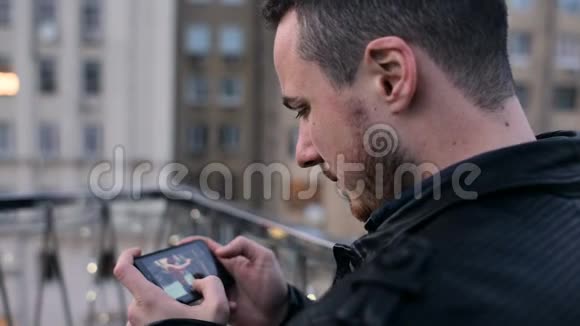 城市屋顶上留着手机胡子的年轻帅哥视频的预览图