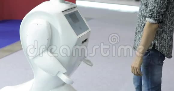 一个人与一个机器人交流把一个塑料机械手臂按到机器人上与机器人握手斯奇菲现代视频的预览图