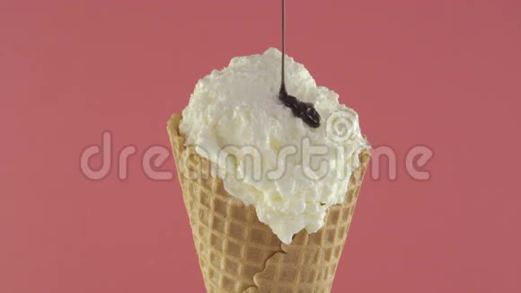 香草冰淇淋和巧克力酱在华夫饼锥粉红色背景视频的预览图