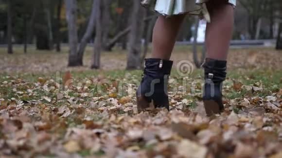 年轻女子在秋天落叶的背景下跳舞走在公园里视频的预览图