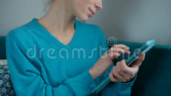 年轻的女人穿着绿松石毛衣在绿色的沙发上放着叶子片视频的预览图