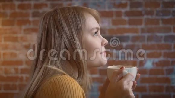 年轻的美女浪漫的女人在咖啡馆喝热咖啡快乐放松的女孩享受一杯温暖的热气腾腾的饮料视频的预览图