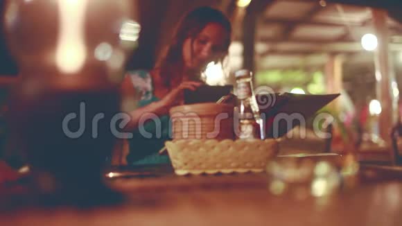 年轻漂亮的女人在户外咖啡馆休息在美丽的bokeh灯上看着大海的菜单1920x1080视频的预览图