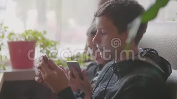 孩子们坐在咖啡馆里玩智能手机慢动作视频游戏青少年社交媒体视频的预览图