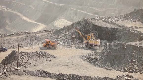 挖土机和翻斗车在采石场大型黄色挖掘机将矿石装入翻斗车工业外部视频的预览图