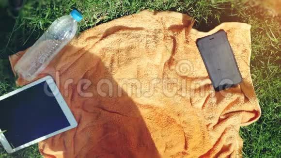 美丽的年轻女子戴着太阳镜躺在草地上听着音乐唱着歌俯视图3840x2160视频的预览图