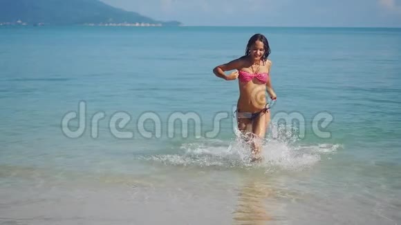 年轻的黑发女人从海里缓慢地跑到海滩1920x1080视频的预览图