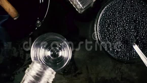 杯子里的慢动作伏特加和黑色背景下的鱼子酱视频的预览图