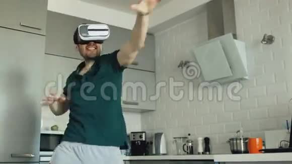 有趣的年轻人在虚拟现实360耳机跳舞时在厨房听音乐和乐趣视频的预览图