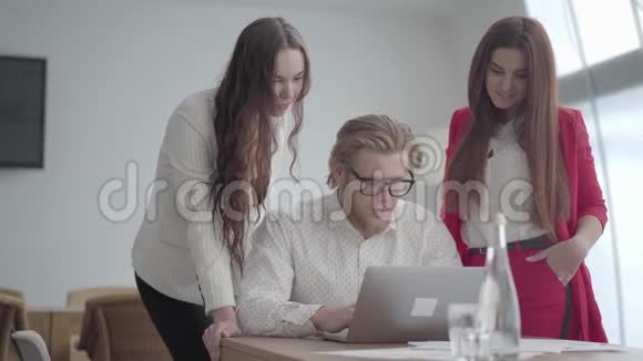 一位戴眼镜的金发男子坐在一间舒适的办公室里桌上放着上网本两个穿正式服装的女孩视频的预览图