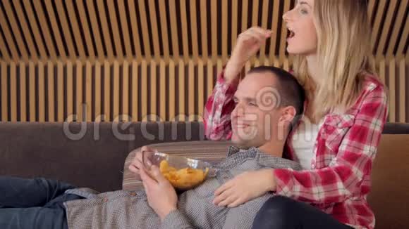 一对夫妇在沙发上看电影一边吃零食视频的预览图