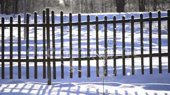 雪片落在明亮的阳光下冬天的雪覆盖了农村的篱笆离焦效应视频的预览图