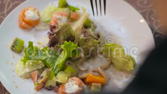 桌子上放着凯撒沙拉的盘子一个拿叉子的女人正在吃沙拉视频的预览图
