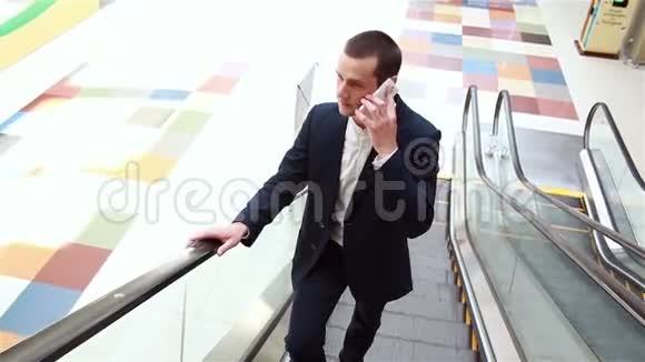 商人坐在自动扶梯上打电话视频的预览图