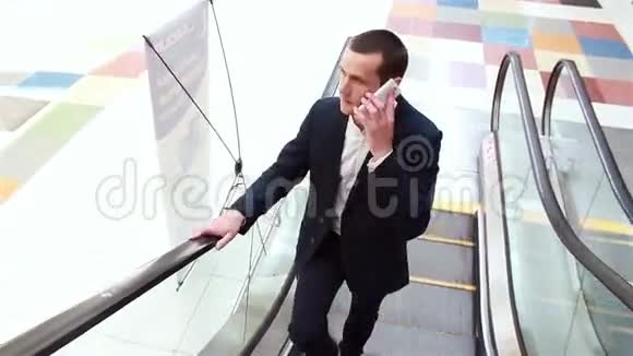 商人坐在自动扶梯上打电话视频的预览图