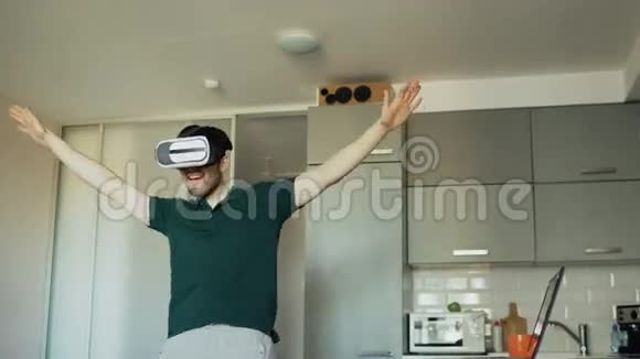 有趣的年轻人在虚拟现实360耳机跳舞时在厨房听音乐和乐趣视频的预览图