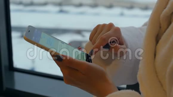 一个年轻漂亮的女人站在窗边从手机里发信息视频的预览图
