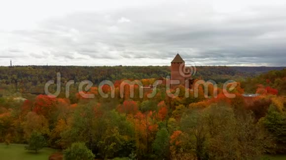 鸟瞰古老的图拉伊达城堡的秋天景观周围环绕着五颜六色的森林明亮的黄橙和绿色树木视频的预览图