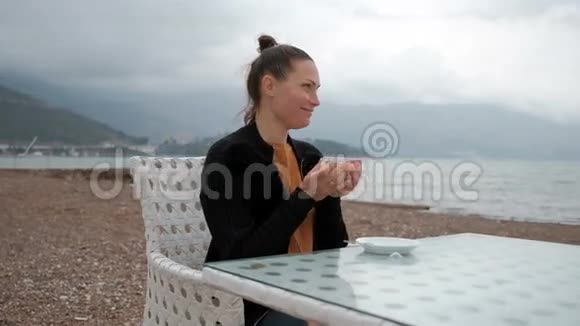 在一个女人的河岸上的咖啡馆里喝着温暖的饮料视频的预览图