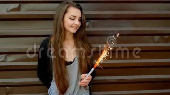 活泼开朗的年轻女孩在涂成棕色的现代墙前玩火花视频的预览图