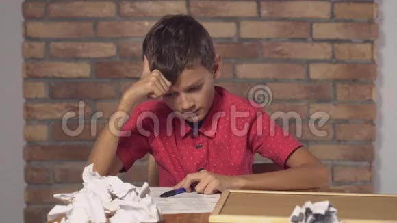 坐在书桌前的孩子拿着一张挂图上面写着红色砖墙上的刻字图案视频的预览图