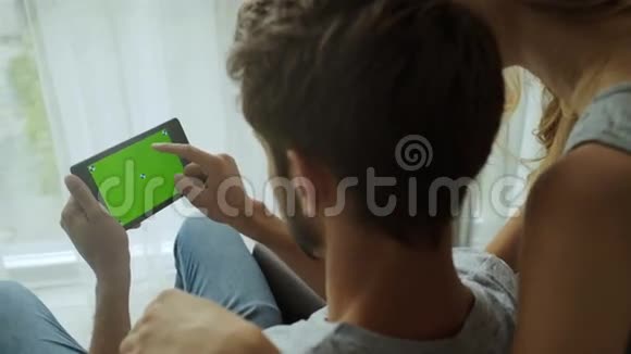 男人和他的女朋友用平板电脑绿色屏幕伟大的模拟最流行的手势使用视频的预览图