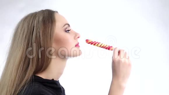 年轻迷人的漂亮兴奋的女人吃五颜六色的棒棒糖慢动作视频的预览图