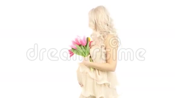 美丽的年轻孕妇穿着粉红色的裙子上面有郁金香白色视频的预览图