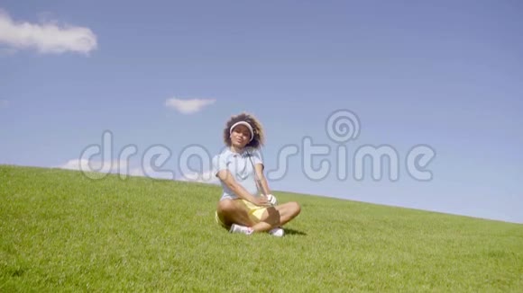 少女高尔夫球手坐在绿色的地上视频的预览图