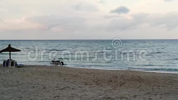 日落时分一对夫妇坐在沙滩上视频的预览图
