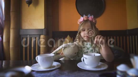 一个小女孩正和她的填充兔子在一家舒适的咖啡馆里喝茶视频的预览图