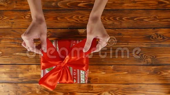 女孩她的手正在用红丝带打开礼品盒上面的风景慢动作视频的预览图