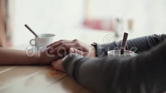 情侣手的特写两只手牵着手用勺子把空杯子放在桌子上视频的预览图