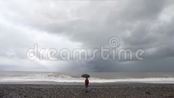 带着雨伞的女人靠近暴风雨的大海视频的预览图