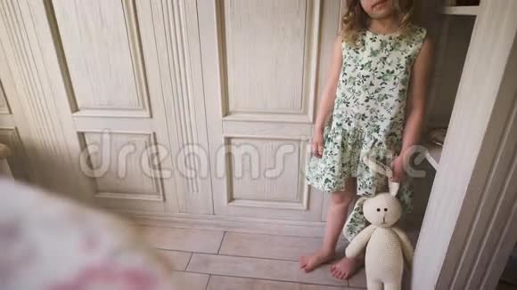 一个可爱的小女孩站在白色的房间里抱着一只毛绒兔子视频的预览图
