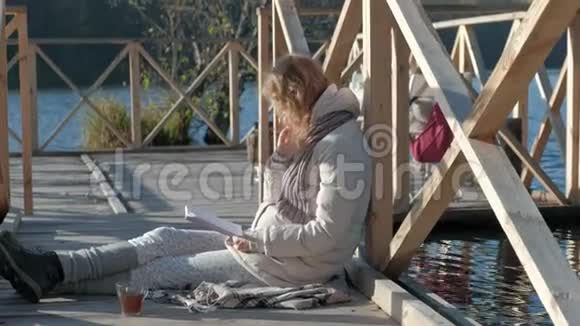 秋河附近的桥上的女人读一本书吃一个苹果视频的预览图