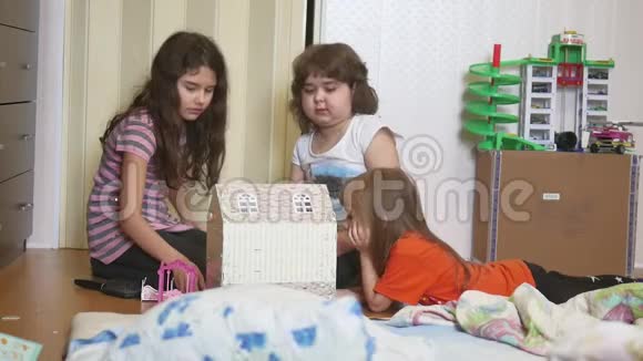 可爱的小女孩在玩玩具在室内亲手制作的纸盒娃娃屋视频的预览图