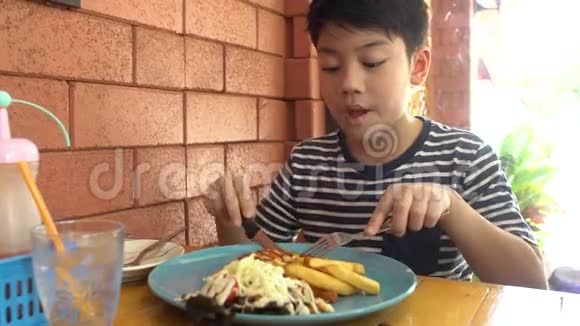 小亚洲小孩在餐馆吃猪肉牛排视频的预览图