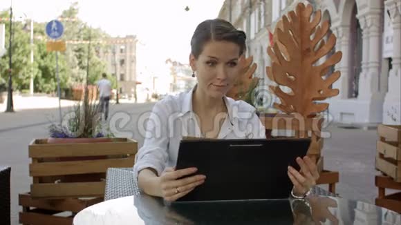 有魅力的女人从咖啡馆的菜单上向服务员点餐视频的预览图