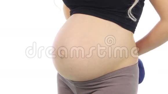 孕妇抱着蓝色的婴儿罩到她的腹部等待婴儿白色特写视频的预览图