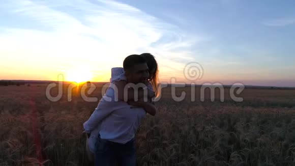 一对年轻漂亮的夫妇在麦田里日落背景的剪影慢动作视频的预览图