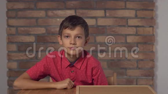 坐在书桌前的孩子拿着一张在背景红砖墙上有刻字趋势的挂图视频的预览图