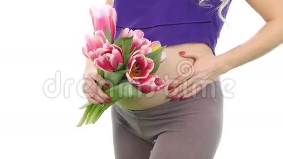 孕妇抱着她的肚子和郁金香花束白色特写视频的预览图