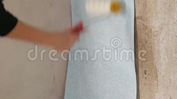 蓝色墙纸用专用的施工滚筒粘在墙上视频的预览图