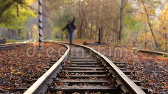 一个人走下火车轨道的背景金色秋天的森林一个男人走近摄像机视频的预览图