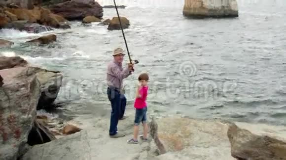 带小孩的老人把鱼竿扔到海里视频的预览图