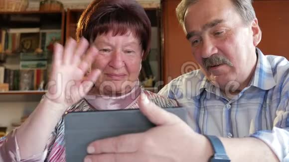 一对老年夫妇通过连接平板电脑的视频与他们的孙子进行交流一男一女在和视频的预览图